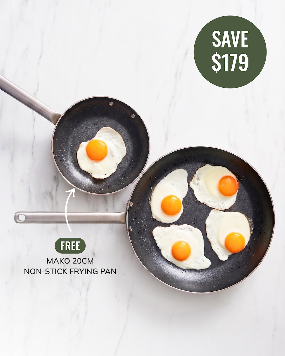 Set of two nonstick frying pans with stainless steel handles on a white marble background. Fried eggs in both pans