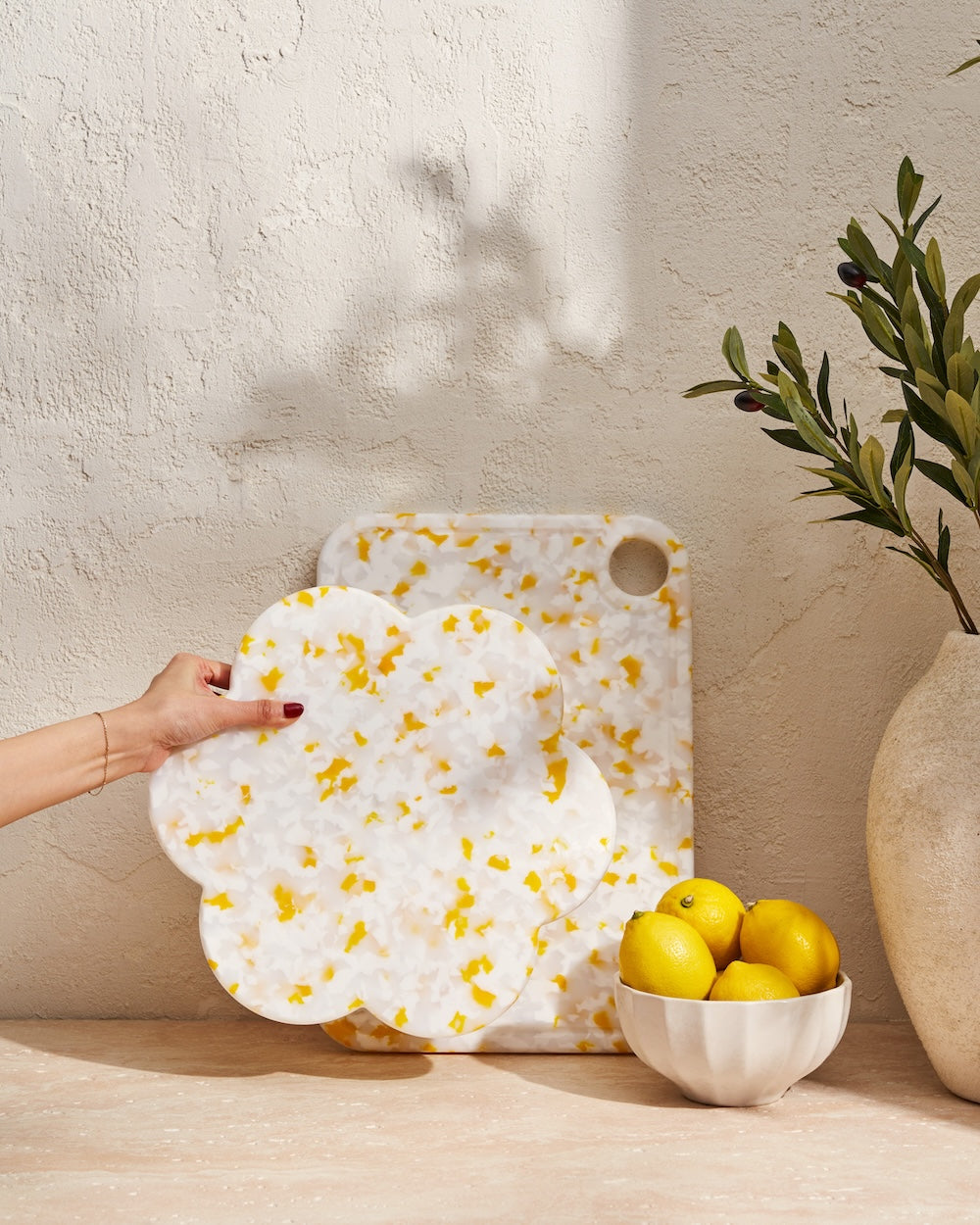 Recycled yellow and white chopping boards with lemons in a bowl on stone countertop