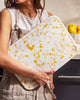 Woman in apron holding Asoke recycled chopping board with Juicy Lemon Meringue pattern by Marion Grasby