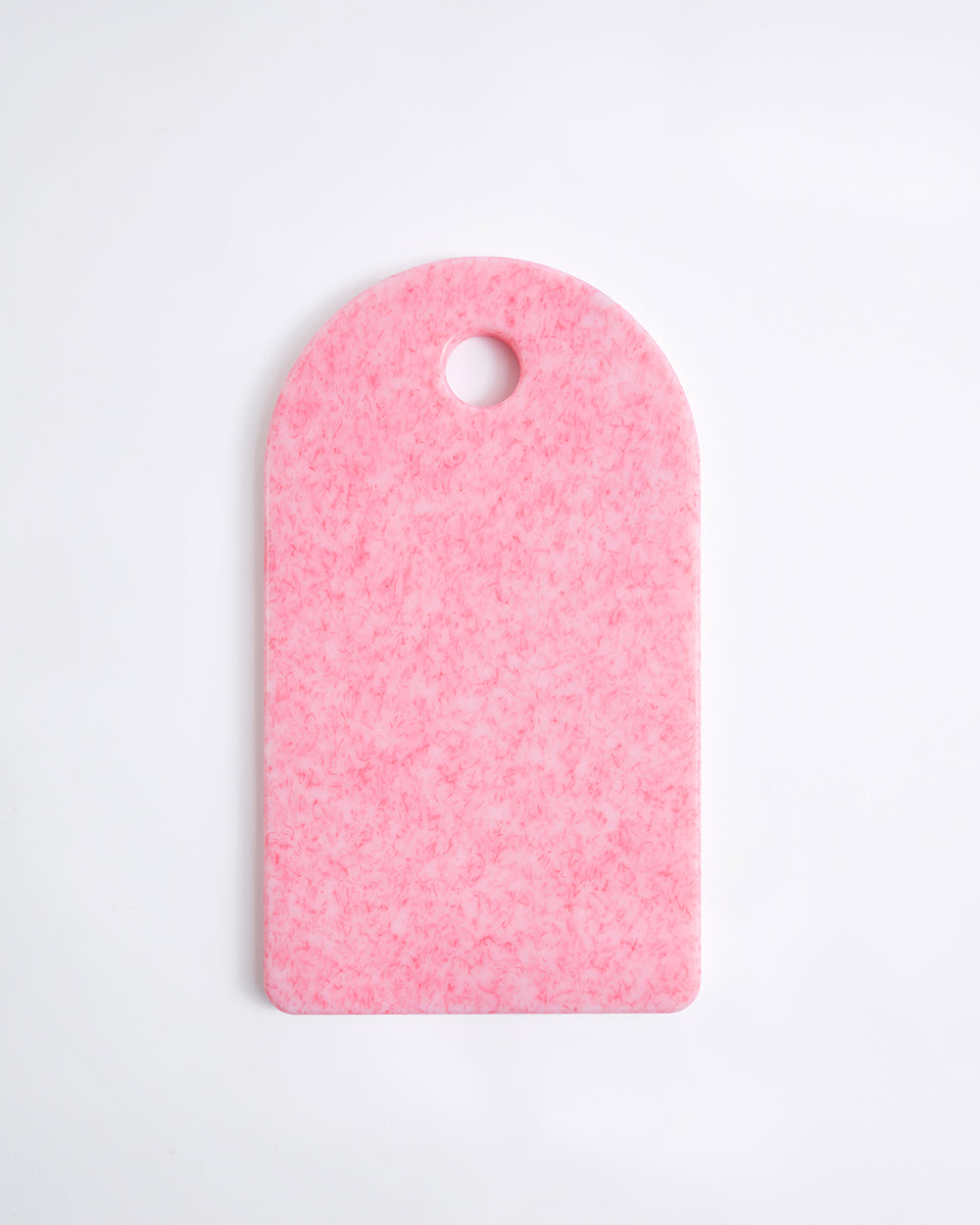 Rectangular pink recycled chopping board with rounded top and hanging hole on white background