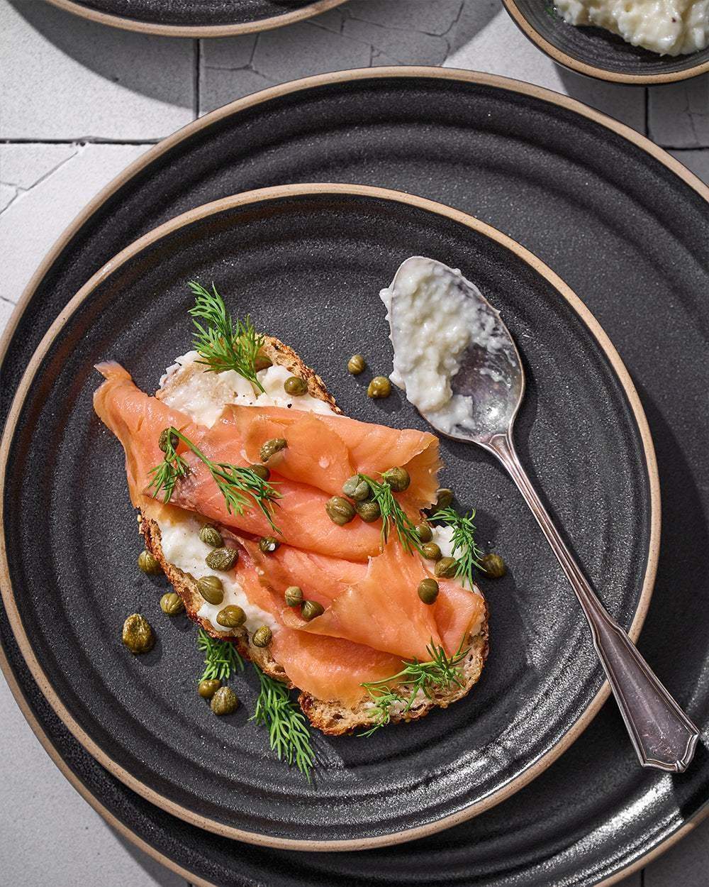 Asoke charcoal ceramic plate with smoked salmon toast, dill, capers, and cream cheese by Marion Grasby