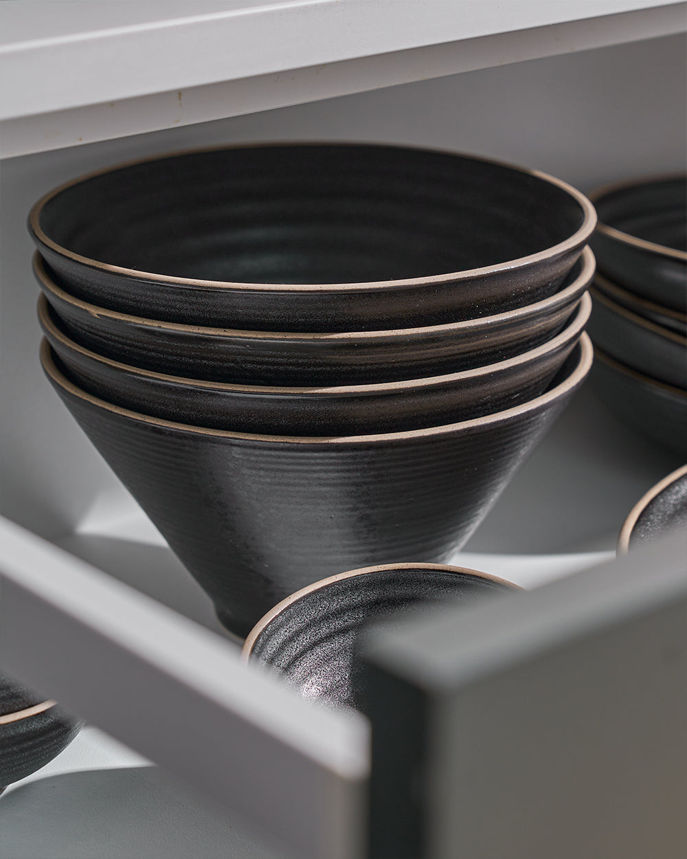 Set of four charcoal ceramic noodle bowls stacked in a kitchen drawer