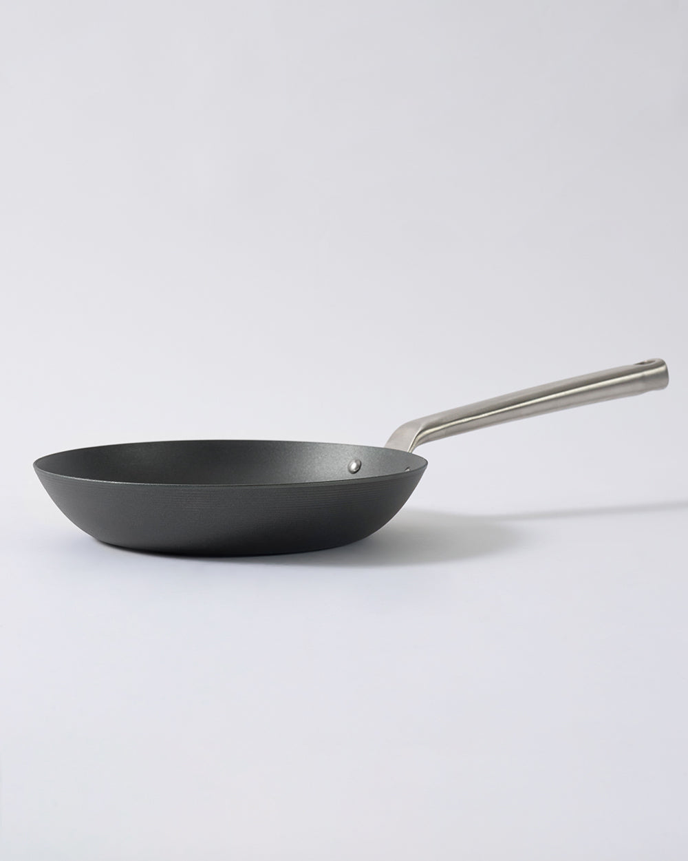 Black steel frying pan with stainless steel handle on white background
