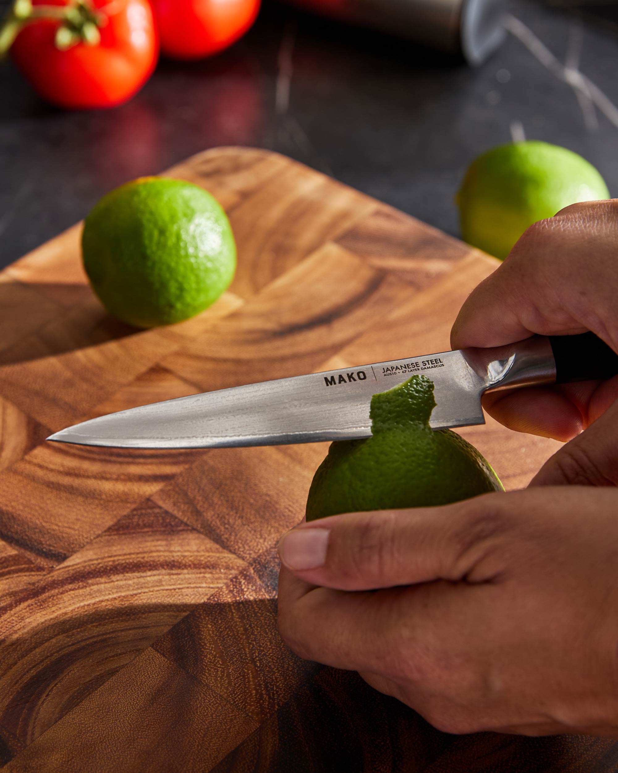 Slicing lime with MAKO Japanese steel kitchen knife on wooden cutting board
