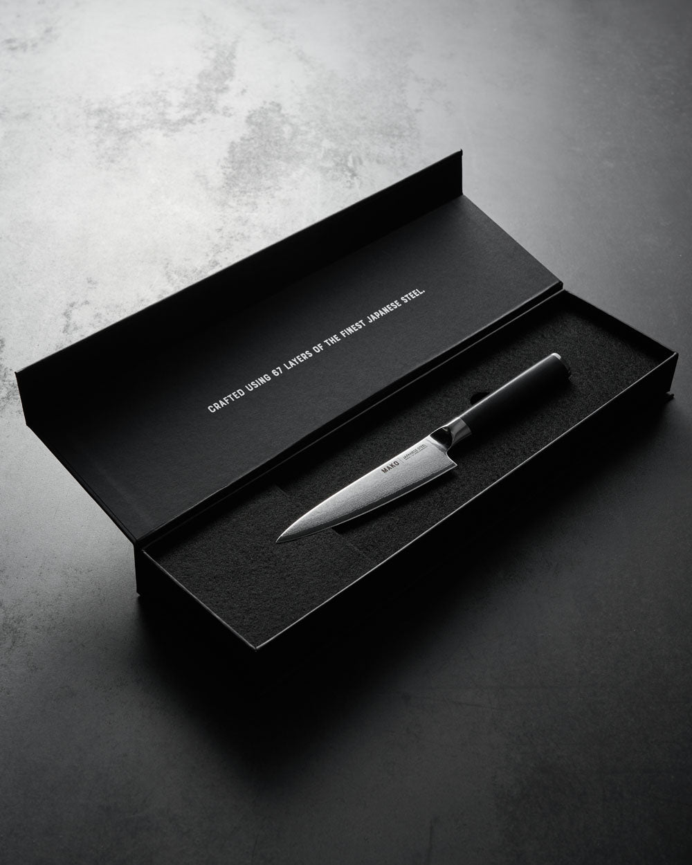 Japanese steel utility knife with olive green handle in black gift box on dark surface