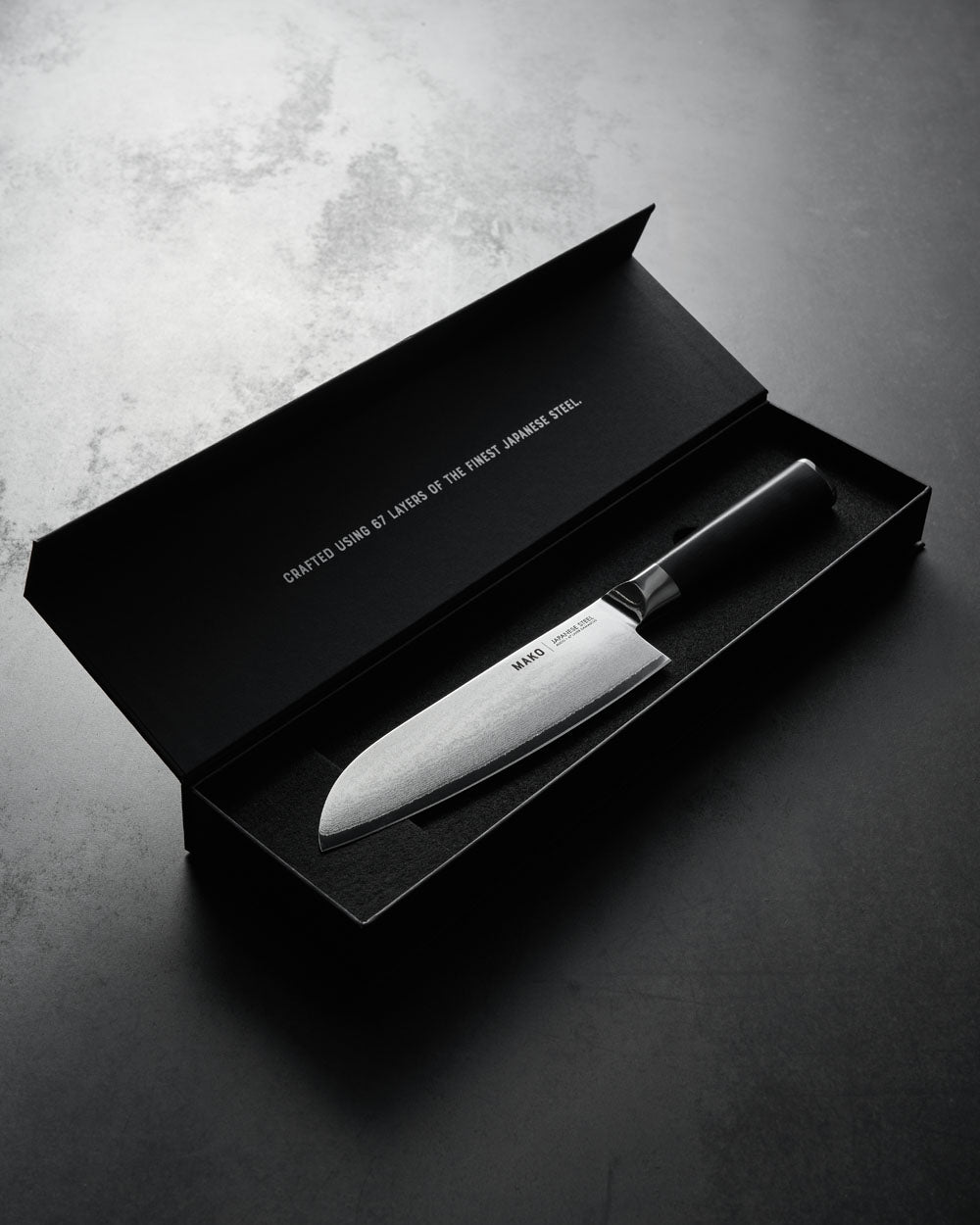 Japanese steel Santoku knife with olive green handle in black gift box on dark surface