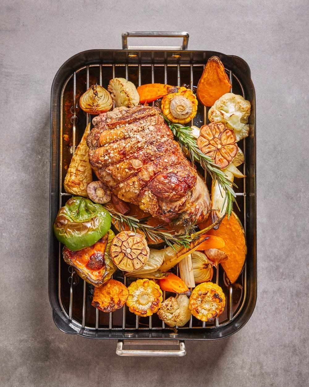 Classic non-stick roasting pan with roast meat and assorted vegetables on a rack