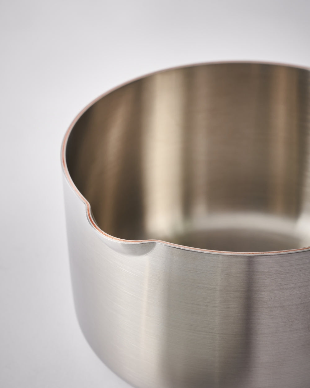 Close-up of stainless steel saucepan with a pouring spout and brushed finish
