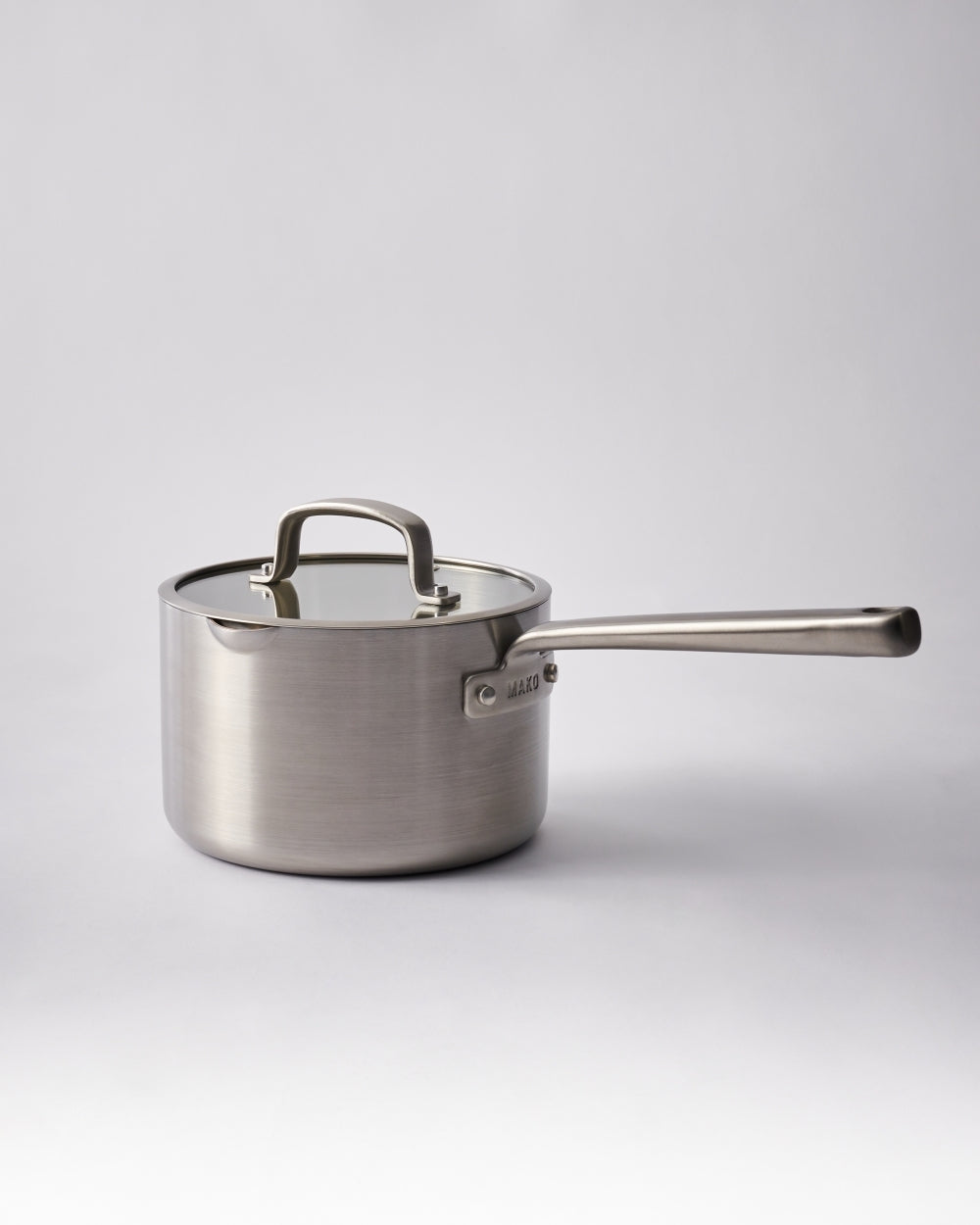 Stainless steel saucepan with glass lid and long handle, ideal for kitchen cooking.