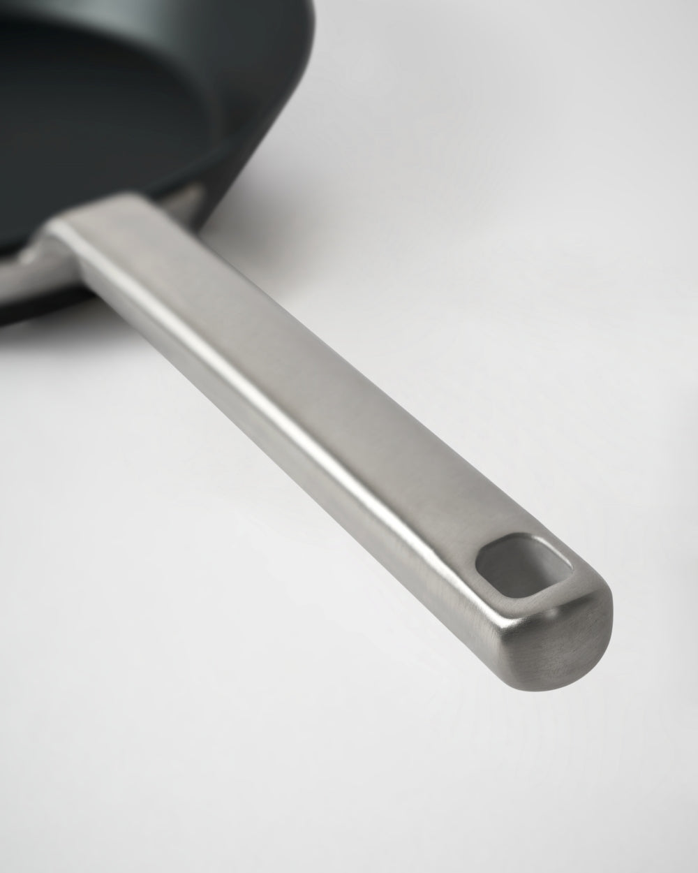 Close-up of a black steel skillet with a stainless steel handle on a light background