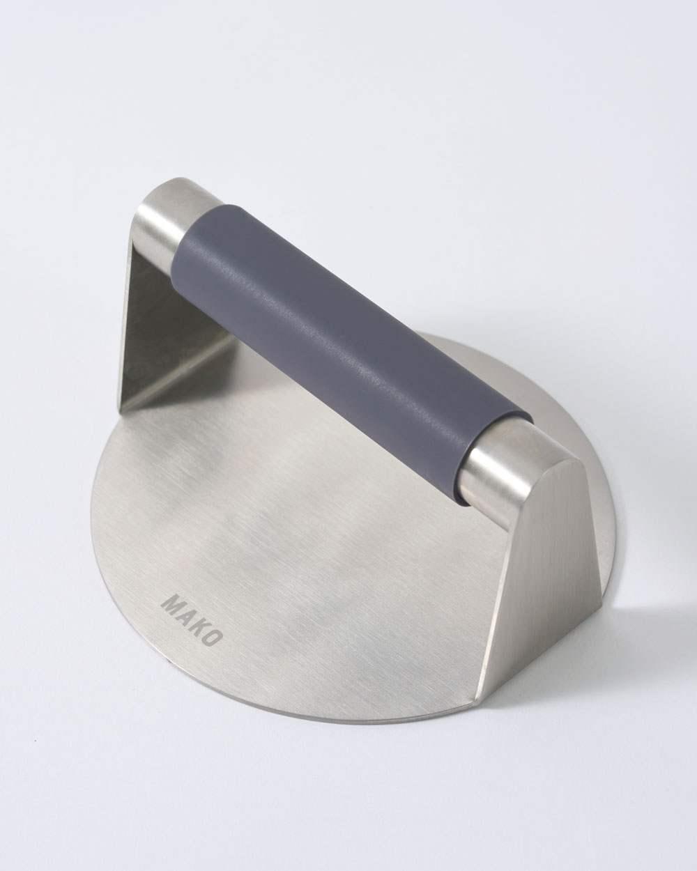 Stainless steel steak press with a non-slip black handle and MAKO engraving on the base