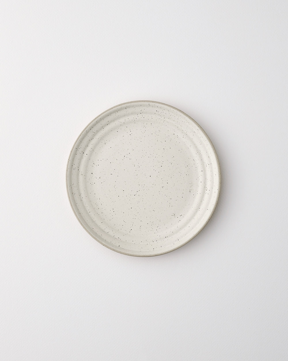 ceramic side plate with speckled glaze on white background