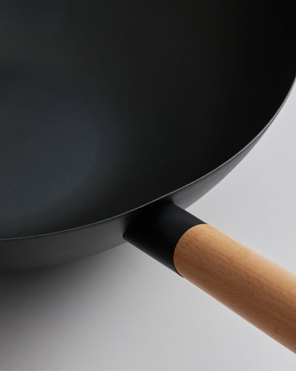 Black steel wok with wooden handle on white background, close-up cookware photo