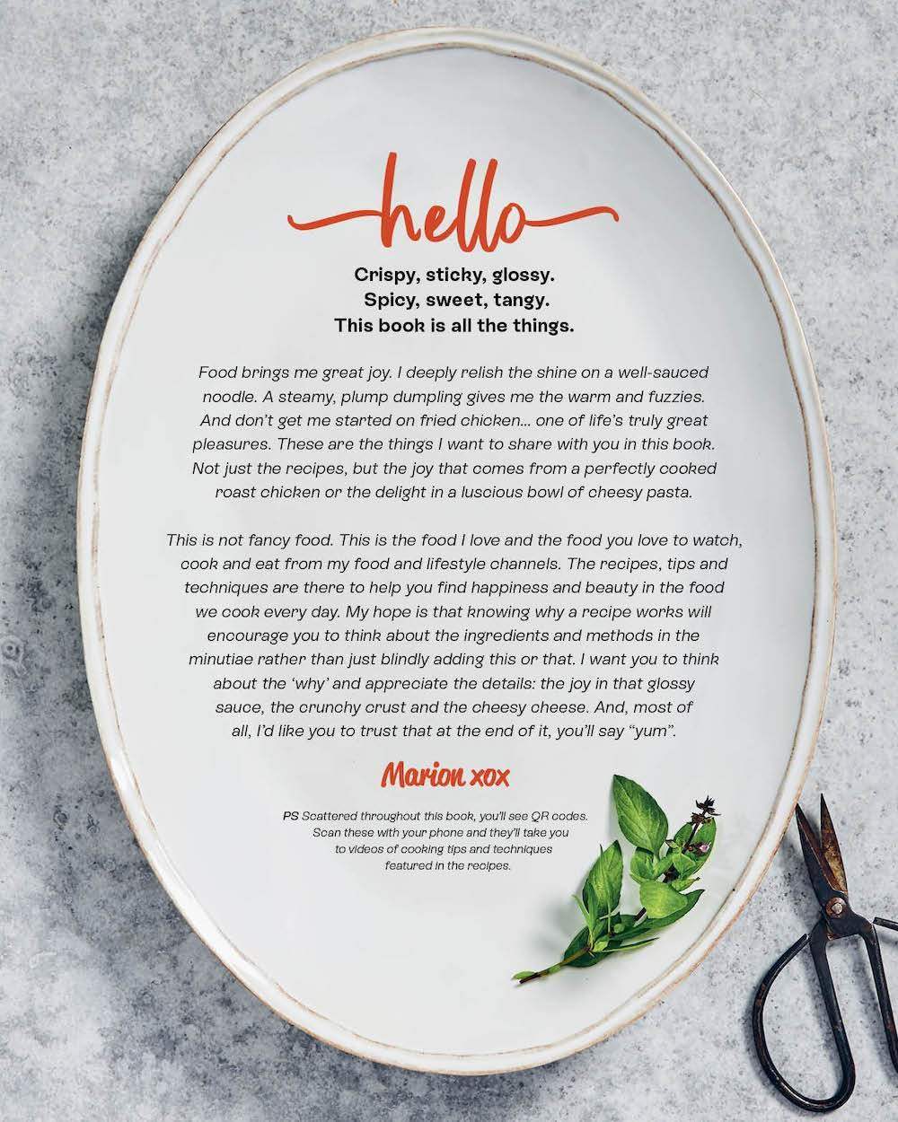Text introduction on white oval plate by Marion Grasby describing her cookbook and cooking philosophy with herbs and scissors nearby