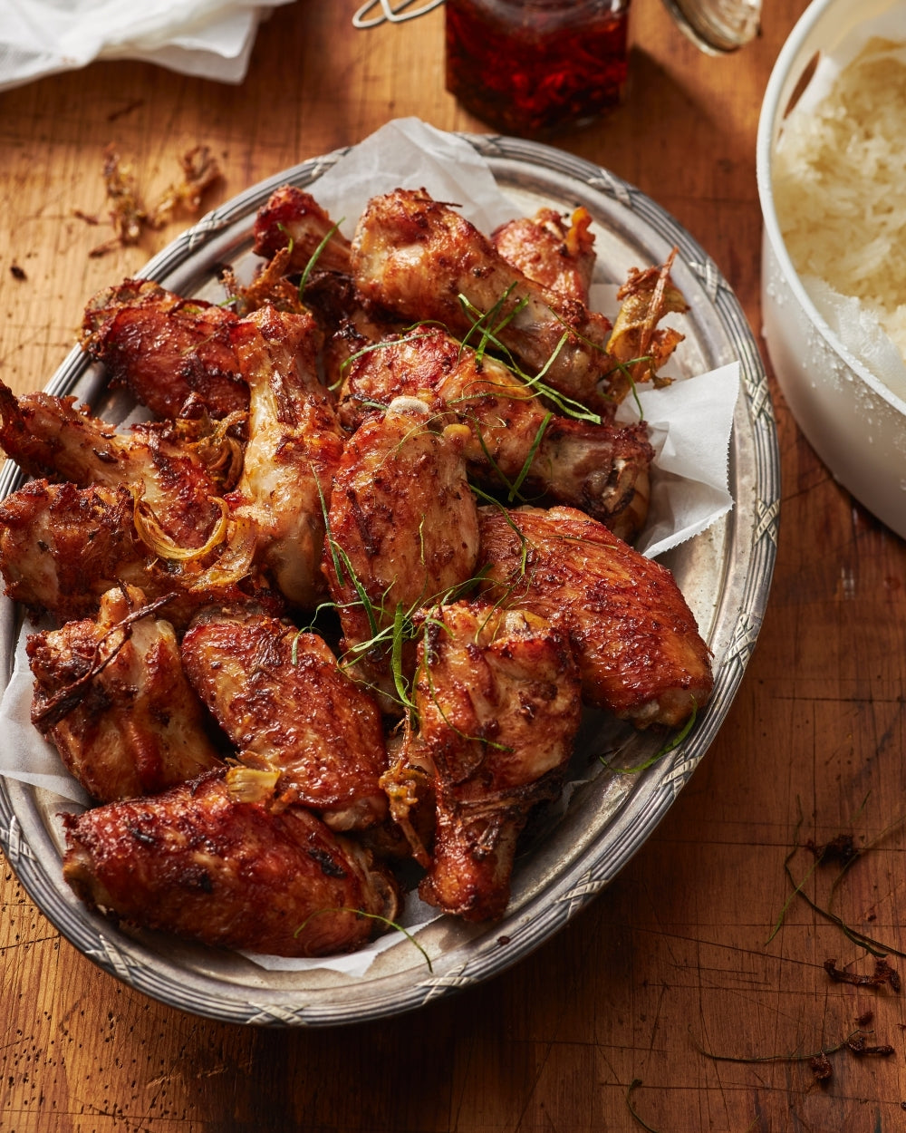 Platter of crispy Asian-style fried chicken wings on parchment, with white rice and herbs